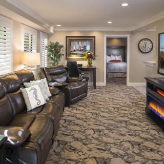 Best Western Plus Humboldt Bay Inn | Eureka, California | Living room with brown couches, TV, black TV stand and view of bedroom